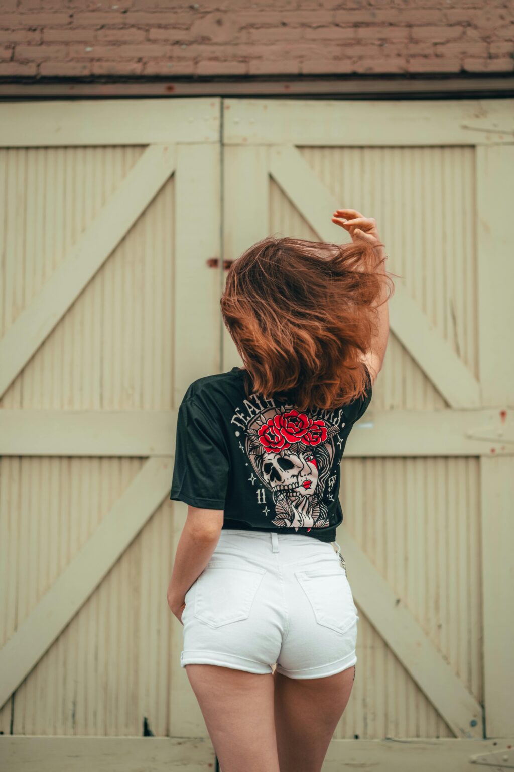 Woman with back turned, wearing shorts and printed t-shirt in urban background. best T-shirt design website