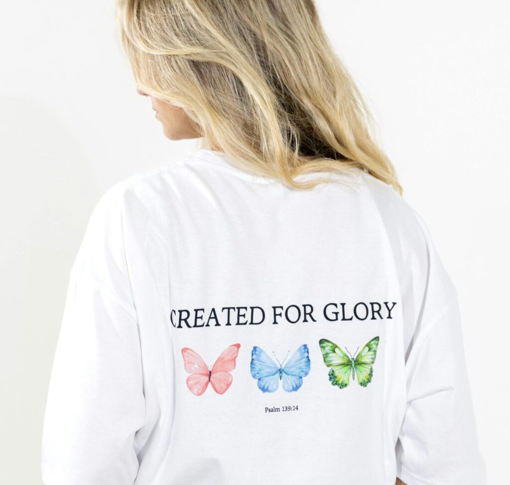 Woman wearing a creative butterfly print designer t-shirt with vibrant colors.